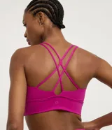 Top deportivo alargado color fucsia, con escote en U y cintura ancha. Posee tiras finas cruzadas en la espalda y copas removibles.