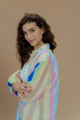 Camisa de mangas largas con puños elásticos y cuello clásico. Presenta un estampado a rayas verticales de colores pastel y cierre frontal con botones.