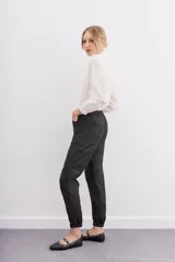 Pantalón babucha negro de lyocell satinado, con elástico en la botamanga, bolsillos plaqué con remaches metálicos y bolsillos cargo en las piernas.