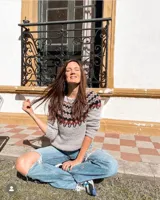 Sweater gris con diseño geométrico en negro y rojo alrededor del cuello, de lana tejido a mano con estilo nórdico.