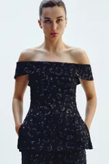 Top chaleco negro con escote recto y hombros descubiertos, con lentejuelas a tono y aberturas laterales.