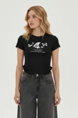 Remera negra de manga larga, corte al cuerpo, con cuello redondo y volados en el ruedo. Estampado frontal en blanco con diseño de mariposas y texto.