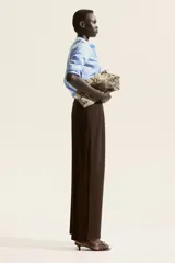 Pantalón sastre marrón de corte ancho, con pinzas y cinturón decorativo con hebilla metálica.