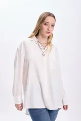 Camisa blanca de lino de manga larga con cuello clásico, cierre frontal con botones y bolsillo en el pecho.