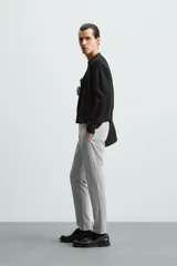 Pantalón largo de vestir gris claro con estampado de cuadros, corte slim fit y cintura elástica. Confeccionado en tejido con alta elasticidad, bolsillos frontales y cierre frontal con cremallera y botón.