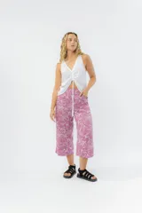 Pantalón culotte color lila con estampado de hojas blancas, de tiro medio y corte recto. Presenta cintura elástica en la espalda y bolsillos laterales.