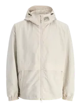 Chaqueta shell ligera color beige con capucha y cierre con cremallera. Confeccionada en tejido liviano, delgado y transpirable. Presenta mangas largas con puños de canalé y bolsillos frontales.