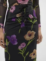 Falda midi negra de tul con estampado floral en tonos rosa, violeta y naranja. Tiene cintura alta con cordón ajustable y abertura lateral.