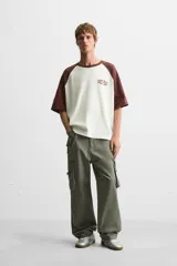 Camiseta blanca con mangas cortas marrones tipo ranglán, cuello redondo y estampado con la frase "Inner Peace" en marrón.