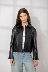 Chaqueta de cuero ovino color marrón oscuro, con cuello camisero, cierre frontal de botones y bolsillos verticales con cierre en la parte delantera. Presenta un corte recto y holgado.