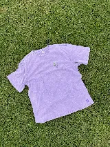 Remera lila con cuello redondo y mangas cortas. Presenta un pequeño estampado de un jarrón con flores en el pecho.