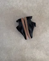 Sneakers bajas de cuero vacuno color bordó con suela marrón.