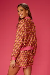 Short de playa con estampado geométrico en tonos naranja, amarillo y rosa. Cintura elástica y ribete rosa.