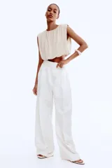 Top cropped color beige, sin mangas, de punto suave y silueta abullonada con efecto drapeado.