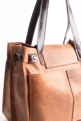 Cartera tipo tote de gamuza color marrón con flecos y detalles en cuero negro charol.