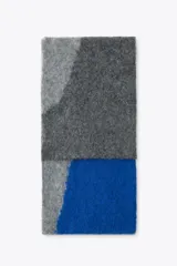 Bufanda rectangular de tejido de punto con diseño geométrico en tonos grises y azul.