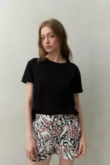 Remera blanca de manga corta confeccionada en algodón liviano con textura levemente jaspeada. Presenta tajos laterales y costura central al frente.