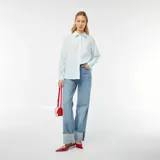 Camisa celeste y blanca a rayas verticales, de corte holgado, manga larga y bolsillo de parche en el pecho.