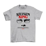 Remera blanca con estampado de la cara de Stephen King y la frase "Based on the novel by Stephen King".