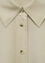 Camisa color beige de corte crop, confeccionada en mezcla de lino y lyocell. Tiene cuello camisero, cierre frontal con botones, manga larga con puños abotonados y lazo ajustable en la cintura.