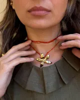 Collar artesanal con dije de flor plateada, realizado con hilo de seda natural teñido a mano.