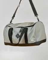 Bolso de viaje gris con base negra, doble asa de mano y correa de hombro ajustable.