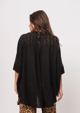 Camisa negra con calados, escote en V, abotonada y manga 3/4.