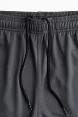 Short deportivo gris de tejido funcional de secado rápido con cintura elástica con cordón ajustable, bolsillos laterales y aberturas laterales en el bajo.