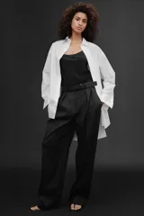 Camisa extra larga blanca de popelín de algodón, con cuello solapa, manga larga con puños, pinzas en la espalda, aberturas laterales y cierre frontal con botones.