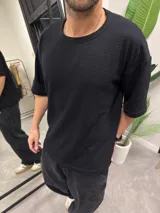 Remera negra de algodón con cuello redondo y mangas cortas. Tejido texturizado.