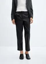 Pantalón negro de efecto piel, corte recto, tiro medio y cintura elástica con cordón ajustable.