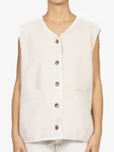 Chaleco oversize confeccionado en tejido teddy color beige. Presenta cuello en V, cierre frontal con botones a contraste y bolsillos laterales aplicados.
