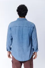 Camisa de manga larga de jean azul claro, con dos bolsillos con solapa abotonada en el pecho.