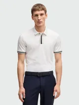 Chomba de piqué de algodón color blanco, corte regular fit, con cuello clásico y tapeta de dos botones. Detalles de rayas en cuello y puños.