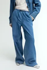 Pantalón denim celeste de corte holgado, con cintura elástica, cordón ajustable, bolsillos laterales y piernas anchas.