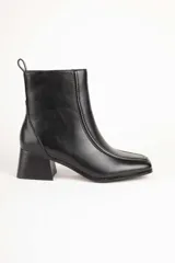 Botas de caña baja en color negro, con cierre lateral y taco cuadrado de 5.5 cm.