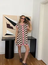 Vestido corto tejido en jacquard de algodón a cuadros marrones y beige, con terminaciones en color rosa. Tiene cuello redondo, botones frontales y corte sin mangas.