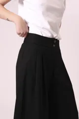Pantalón palazzo negro de tiro alto con pinzas y dos botones en la cintura.