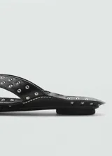 Sandalia negra de cuero con diseño destalonado, punta cuadrada y apliques metálicos.