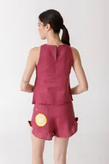 Musculosa color borgoña de lino, con cuello redondo y detalle de botones dorados en los hombros y laterales.