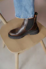 Bota Chelsea de cuero negro con elástico lateral y suela track.