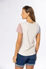Remera de manga corta color beige con bloque de color en mangas: celeste en la manga izquierda y rosa en la manga derecha.