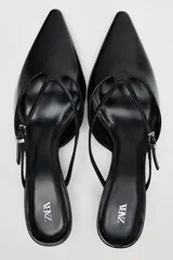 Zapato destalonado tipo mule de cuero negro, con punta fina, tira delantera con hebilla y tacón kitten.
