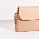 Bandolera color beige con correa larga regulable y tachas plateadas en los laterales.