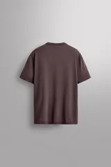 Camiseta color crema de corte relaxed fit, cuello redondo y manga corta. Tiene un texto estampado en el frente y un logo estampado en el ruedo.