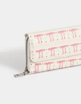 Billetera tipo fichero con estampado de moños rosas y celestes sobre fondo blanco. Tiene cierre superior y solapa con broche.