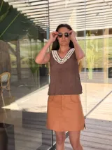 Top negro de cuero con escote en V y apliques de caracoles cosidos a mano en el escote.