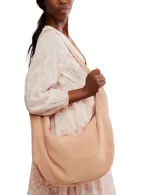 Bolso tipo hobo de gamuza negra, con forma holgada y cierre principal de cremallera. Se lleva al hombro con dos asas de correa delgadas sujetas con argollas metálicas plateadas.