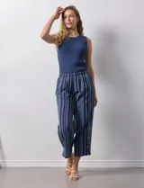 Pantalón de algodón estampado a rayas verticales azules y blancas, marca Erika. Tiene pretina elastizada, bolsillos delanteros, ruedo lateral con tajo y botones decorativos.