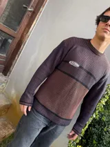 Sweater marrón con rayas horizontales azul marino, cuello redondo y parche con logo bordado en el pecho.